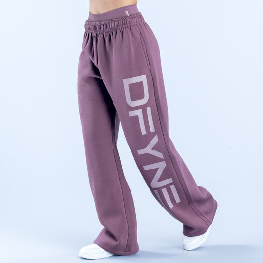 Purple wide-leg jogger pants with elastic waistband and large vertical logo on leg
