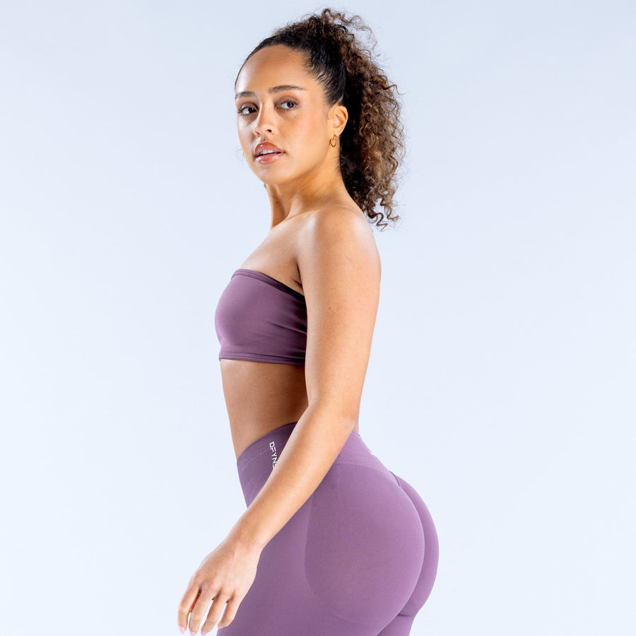 Purple bandeau sports bra with side profile and DRYNE logo patch