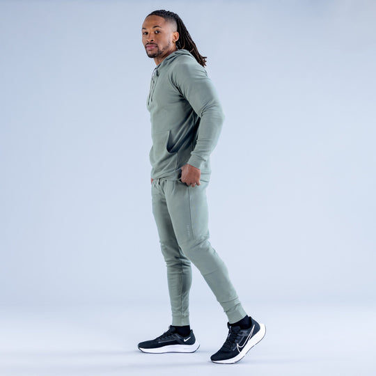Sage green midweight hoodie on model, side profile with drawstring hood