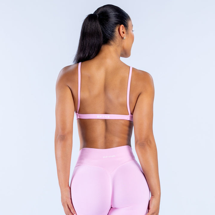 Pink scoop-neck bra with racerback straps and centered back logo band