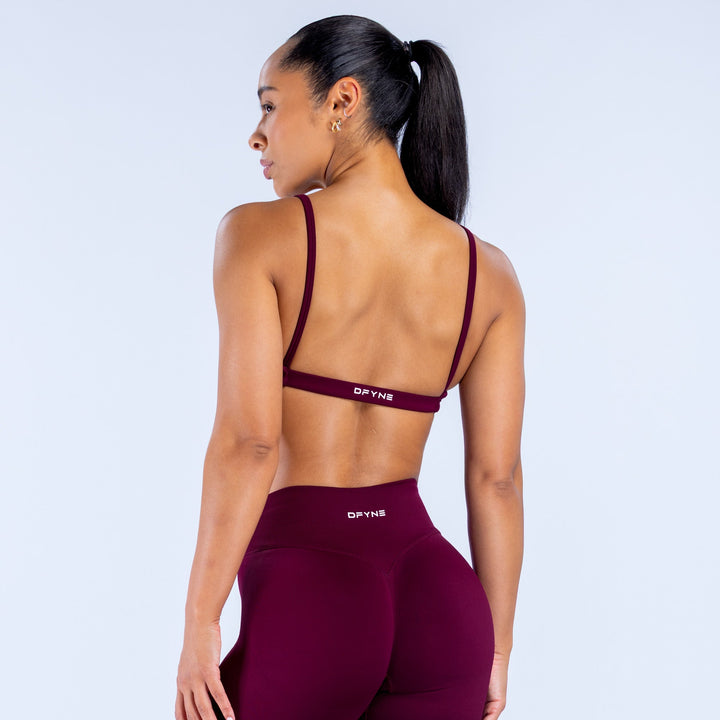 Burgundy scoop-neck sports bra shown from the back with thin straps