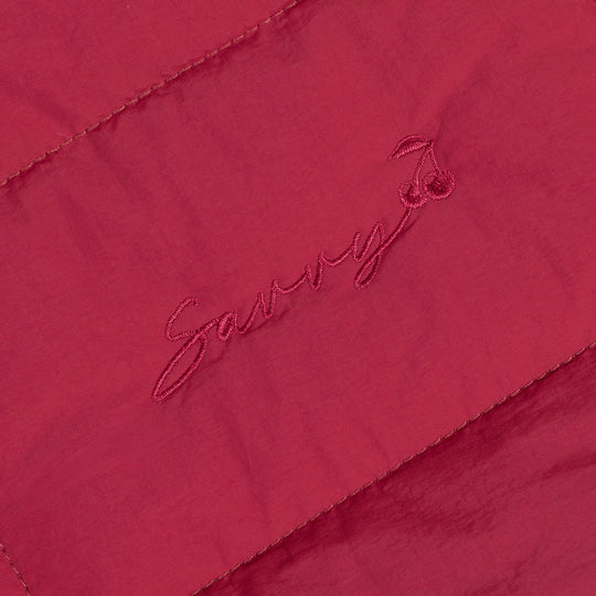 Red fabric patch with embroidered logo on quilted puffer bag.