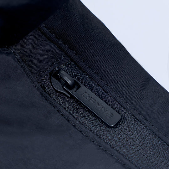 Zipper pull with DKNY logo on dark puffer bag, close-up