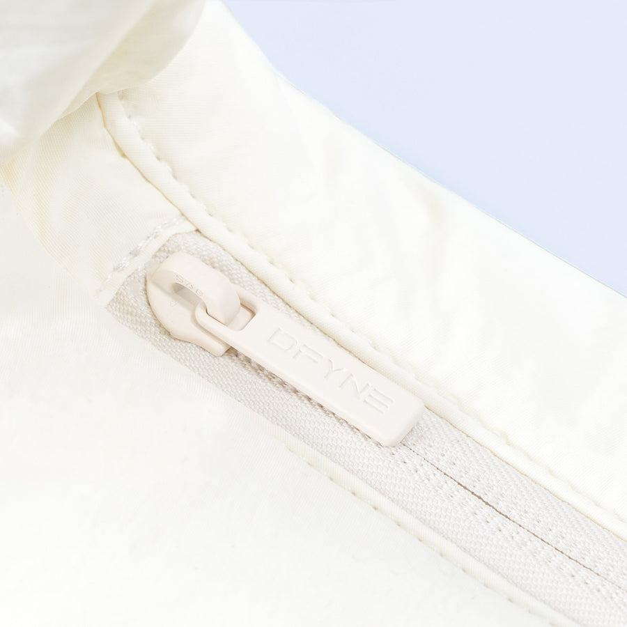 Sav puffer bag close-up of zipper and fabric trim on ivory quilted panel