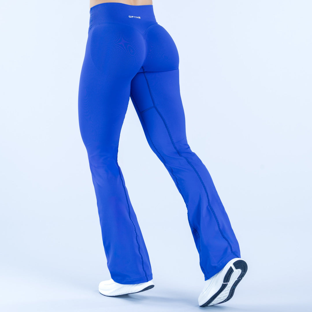 Blue flared leggings with textured seam panels, back view, full length